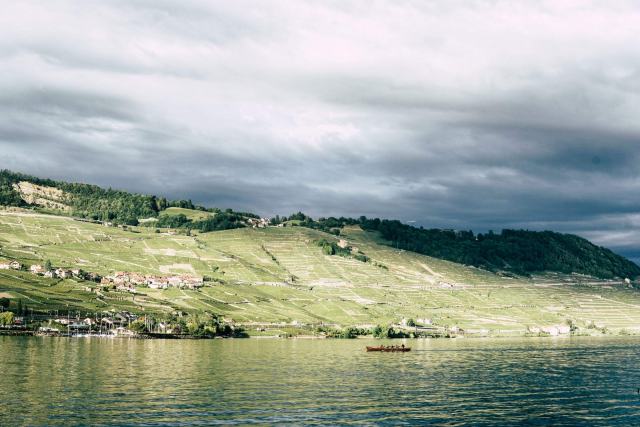 Route du Vignoble : contenu du guide et méthode de travail Coteau de vignes et villages au bord d'un lac, sous un ciel chargé de nuages