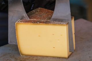 Demi-meule de fromage à raclette dans son support, prête à fondre
