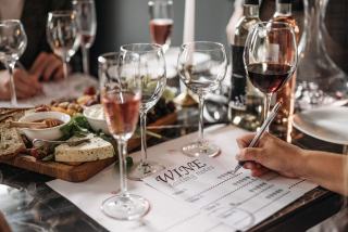 Table de dégustation avec verres de vin, plateau de fromages et fiche de notes
